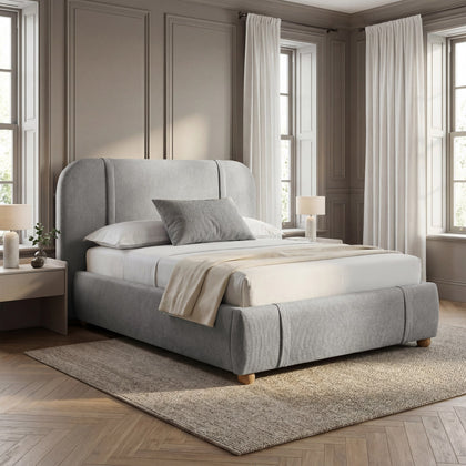 [Double | Grey] Textured fabric bed with channel-stitched curved headboard against warm moulded wall with natural daylight