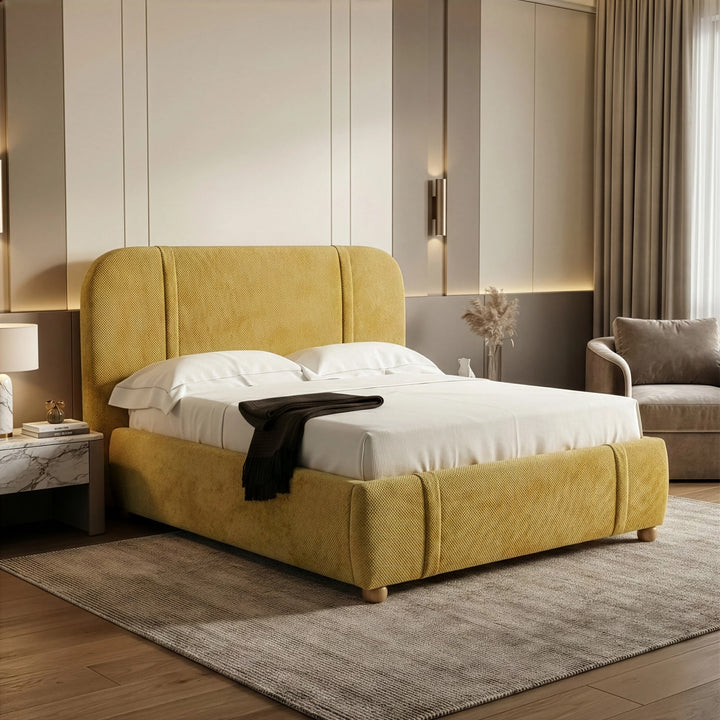 [King | Yellow] Upholstered bed from the side with marble nightstand and brass wall sconces beside feature wall