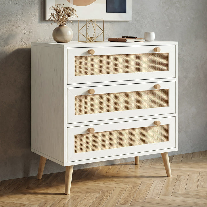 [White] Wovena White Rattan 3 Chest of Drawers, Pine legs angled look against a modern textured grey wall.