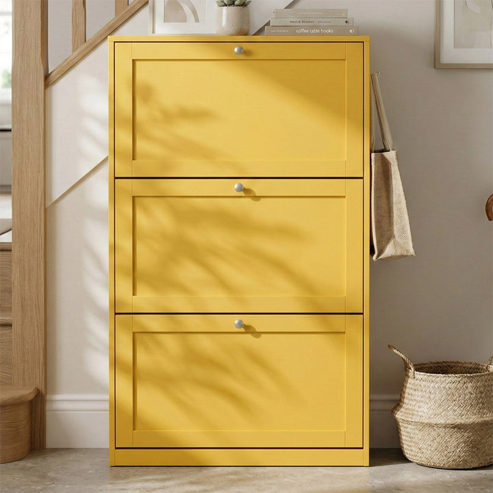 [Yellow]  Shaker Shoe Cabinet closed three-door flip-front unit in hallway setting with woven basket and staircase in background