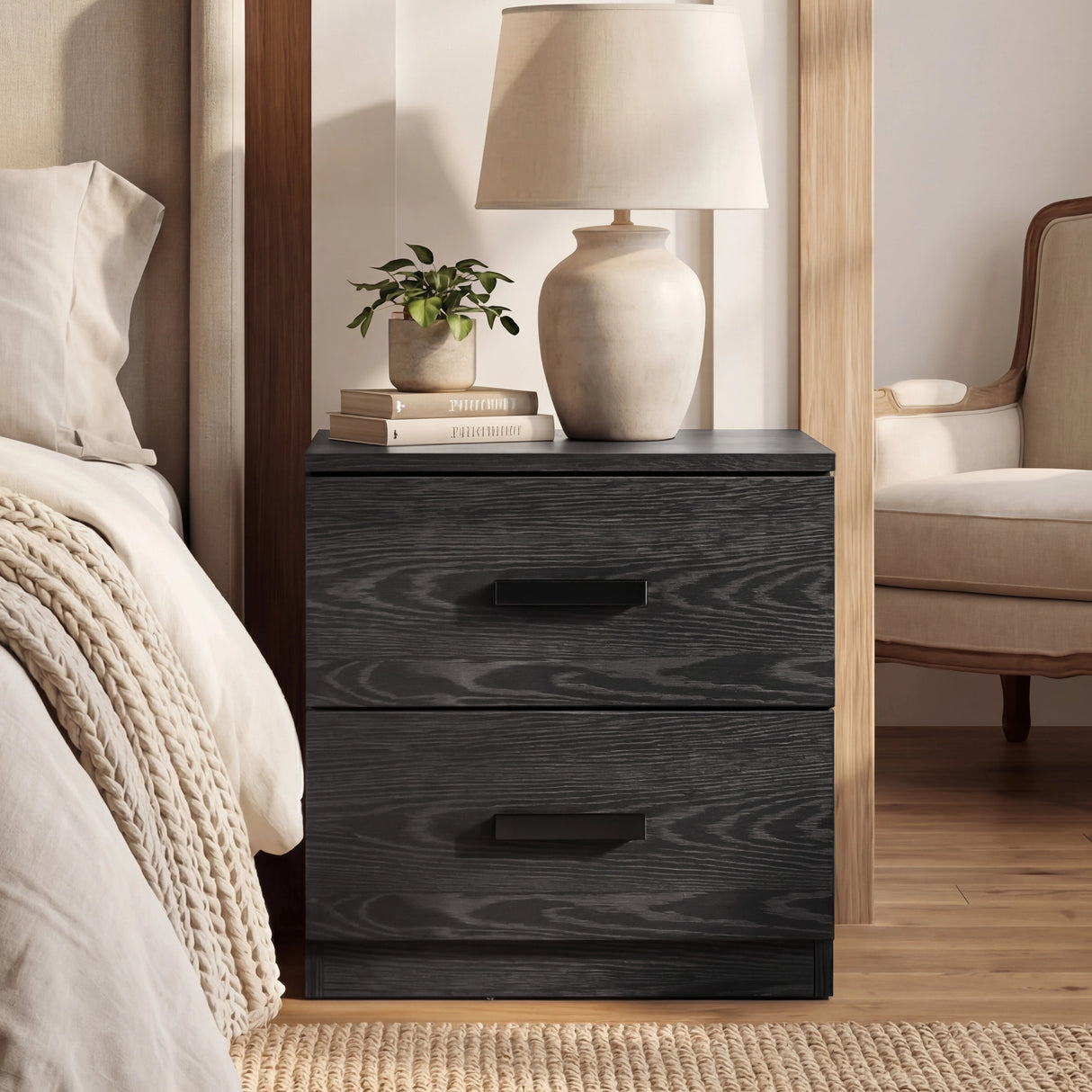 Black two drawer bedside table placed beside bed with textured wood finish and compact rectangular form