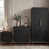 Black bedroom furniture set, including a wardrobe, chest of drawers, and bedside table, placed in a modern room