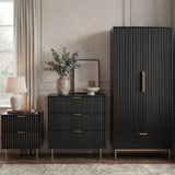 Black bedroom furniture set, including a wardrobe, chest of drawers, and bedside table, placed in a modern room
