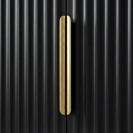 Close detail of a black wardrobe with a vertical golden metal handle against a flutrina door surface