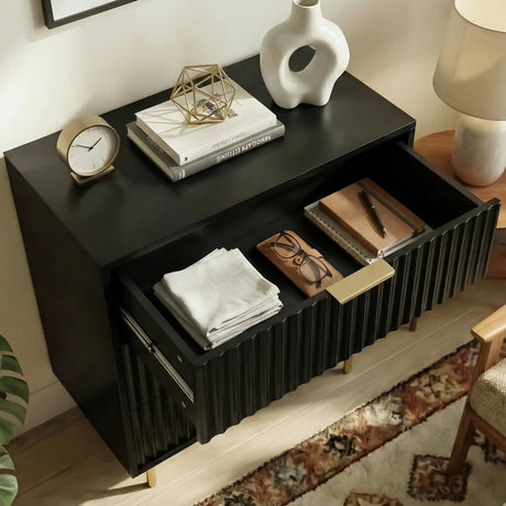 Black bedside table unit beside a bed, shown with an open drawer containing organised storage