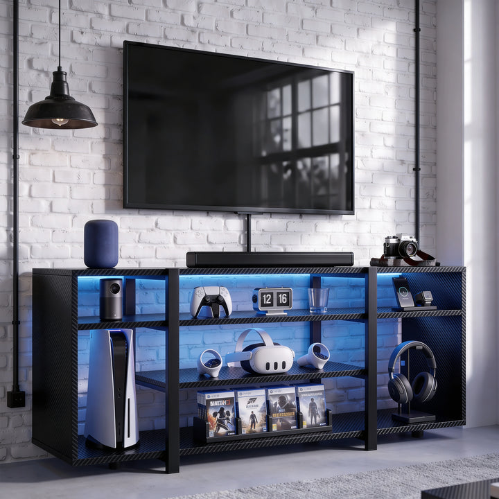 [Black Carbon Fibre] Zelumi TV stand front-facing in a brick-wall gaming room with blue LED shelves, console, VR headset, soundbar, and items on top