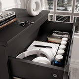 [Black] close-up of open top drawer of black high gloss chest with headphones, books and accessories inside