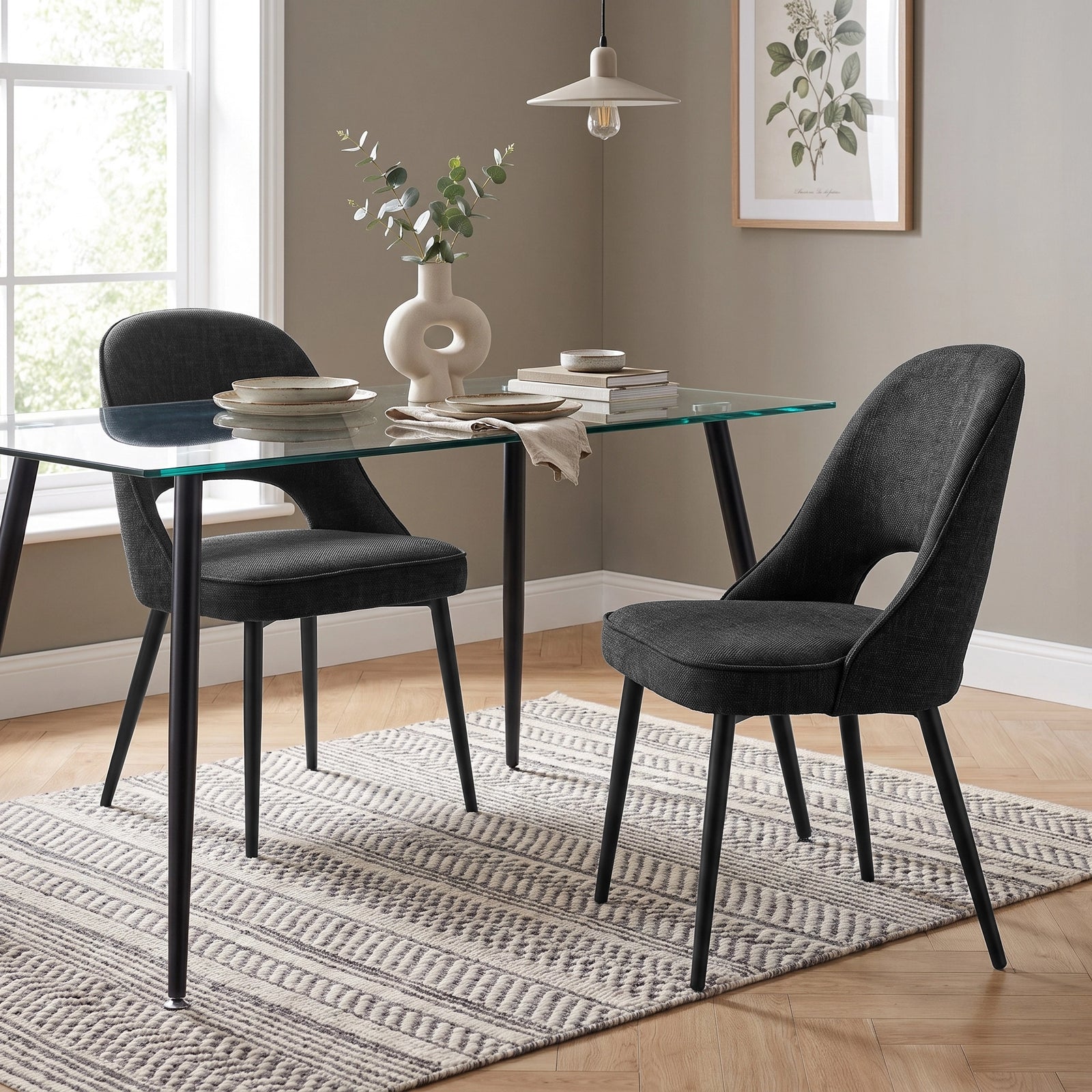 [Black | Set of 2] Pair of curved-back dining chairs at a glass table styled with plates, books and a sculptural vase.