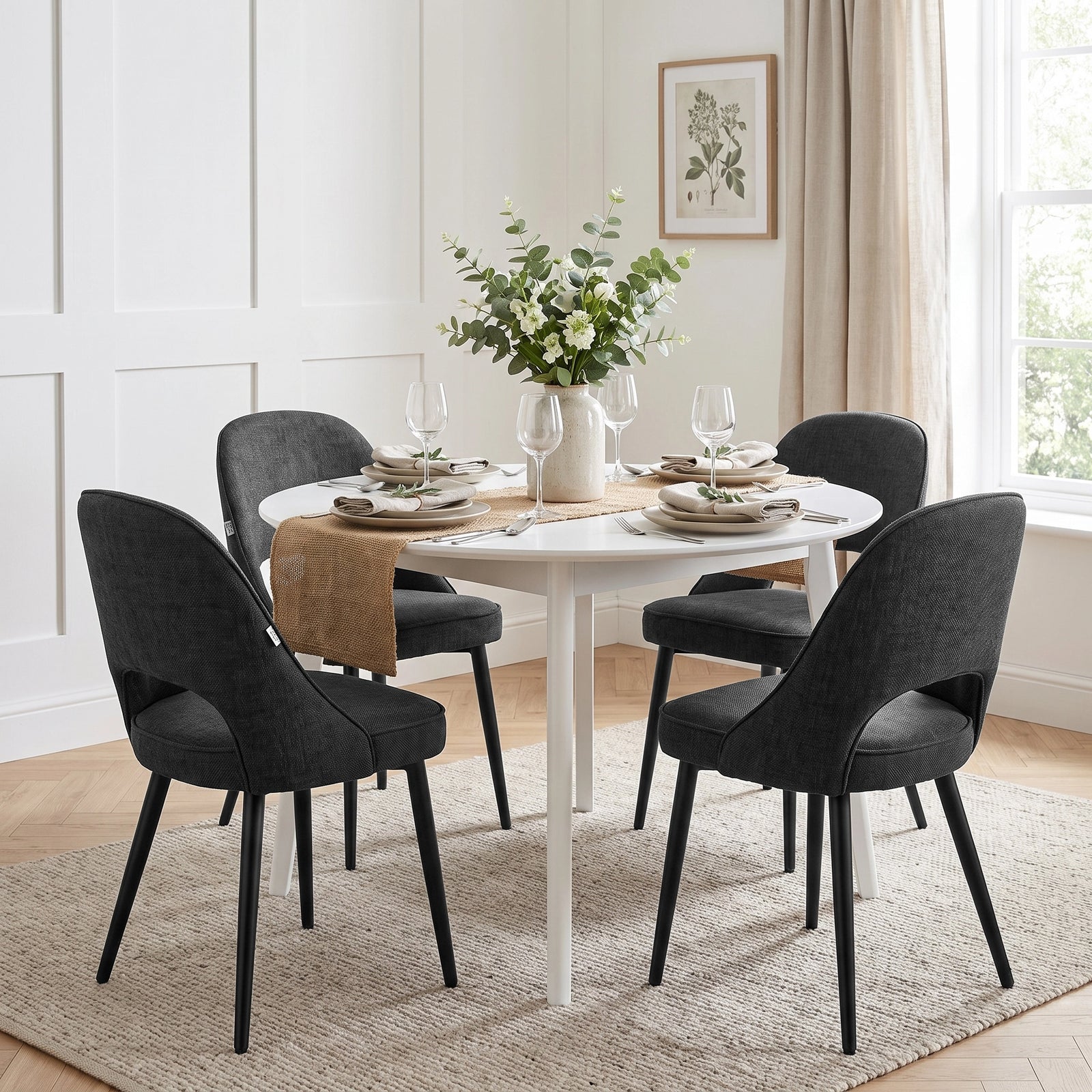 [Black | Set of 2] Two pairs of the comfy black dining room chairs around a round white table with tableware & a flower vase.