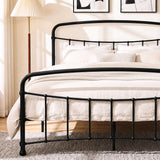[Black | King] Close view of the black curved front rail, vertical bars and cream bedding beside a wooden table.