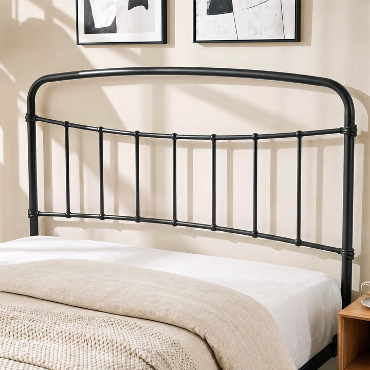 [Black | King] Close-up of the black curved headboard with vertical bars, cream pillows and layered bedding.