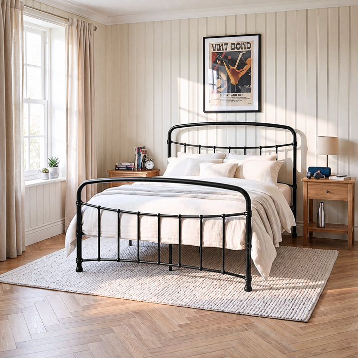[Black | King] Black metal bed frame with cream bedding, wooden side tables and a woven rug in a bright bedroom.