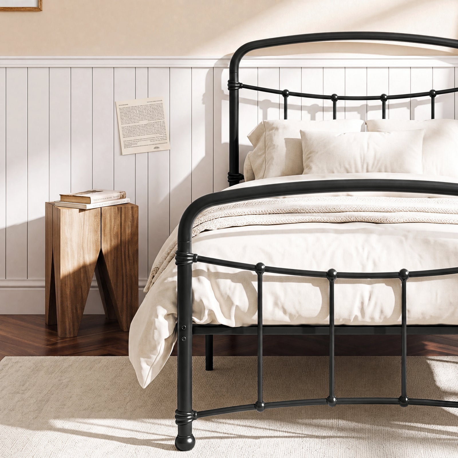 [Black | Single] Close view of the black curved front rail, vertical bars and white bedding beside a small table.
