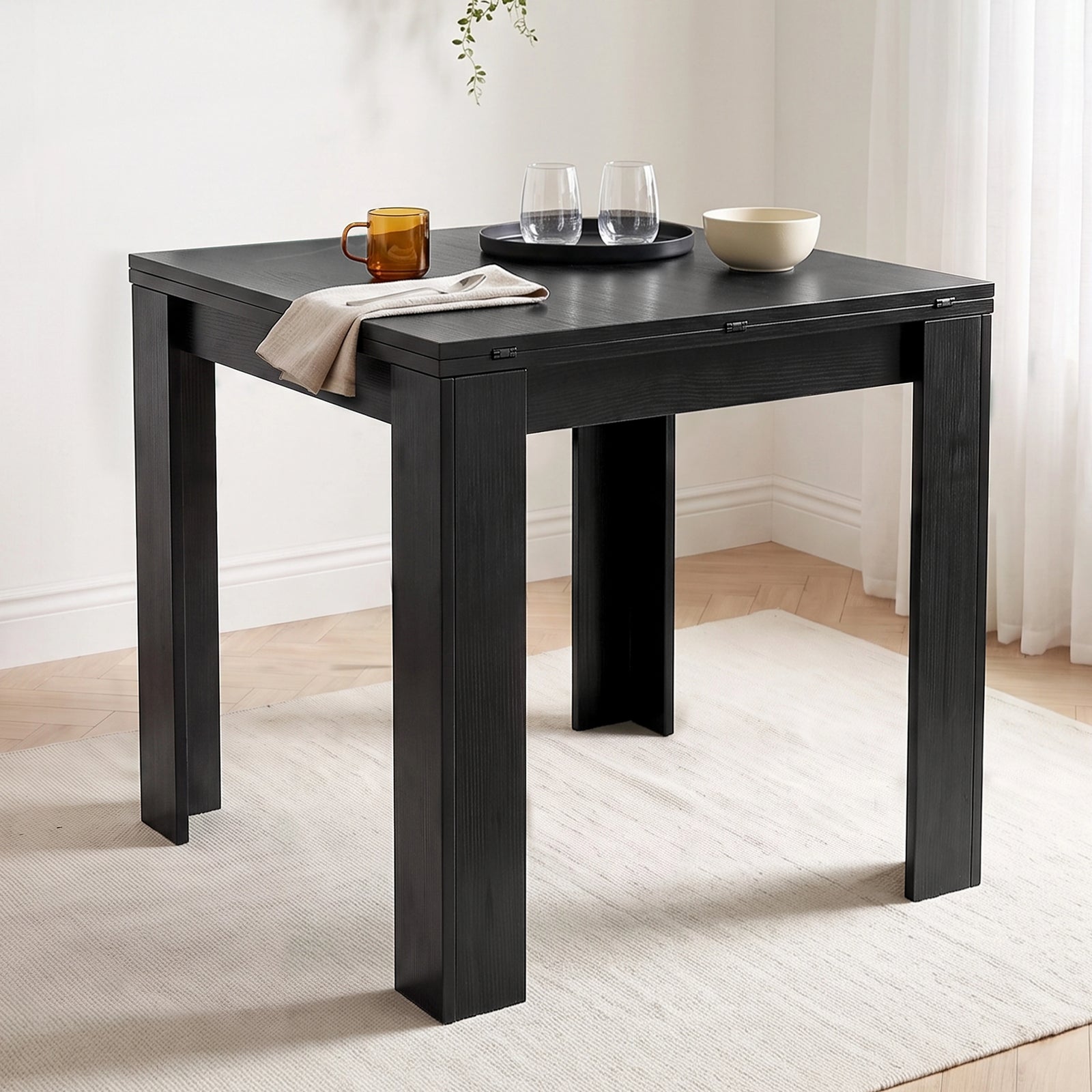 [Black] Close-up wood-grain closed tabletop, steel hinges, wide legs, mug, two glasses, white bowl, napkin and spoon