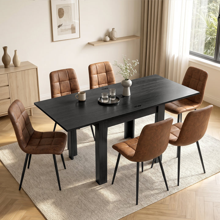 [Black] Extended flip-top dining table with six brown chairs, cup, two glasses and flower vase in a bright dining room.