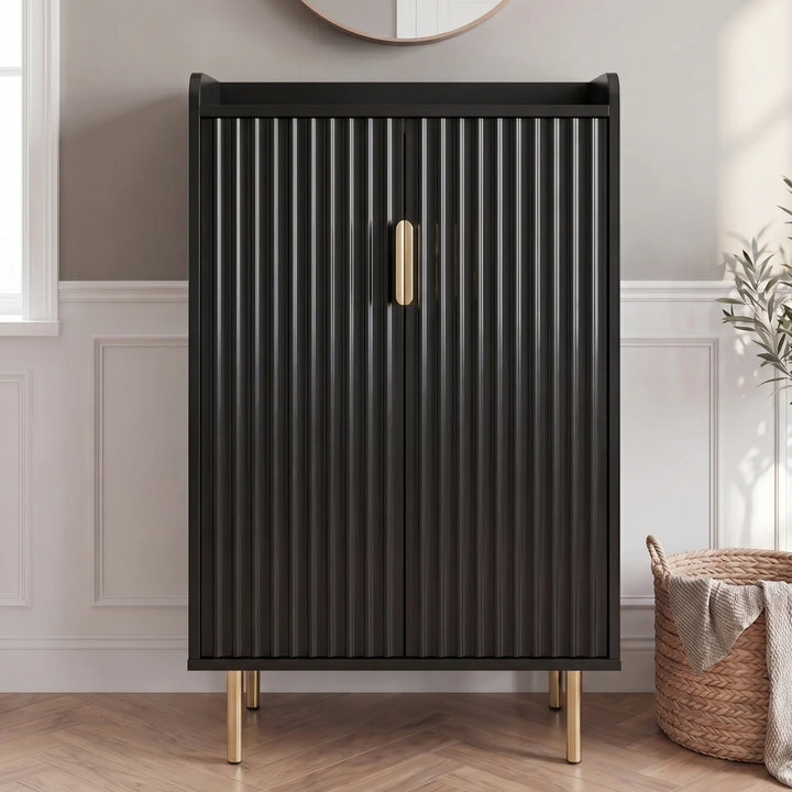 [Black] Fluted Shoe Storage Cabinet shown closed against panelled walls with round mirror, olive plant, and woven basket in a sunlit hallway