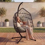 A girl seating in direct sunlight on black hanging egg chair with a strong stand and cushions inside for more comfort