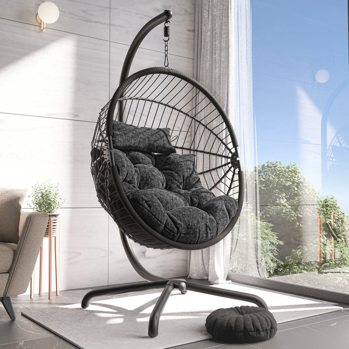 Black hanging chair with cushion in a modern room with large window