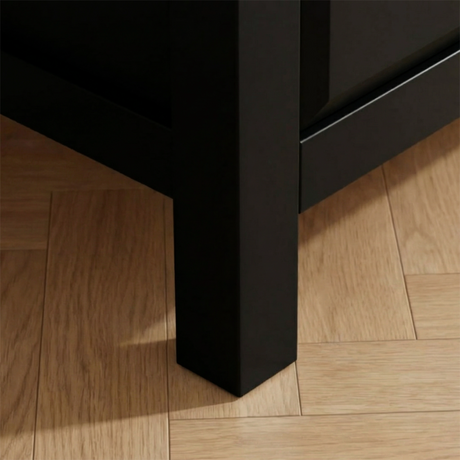 [Black] Haven chest close-up of the solid square matte black leg sitting on warm oak herringbone parquet flooring