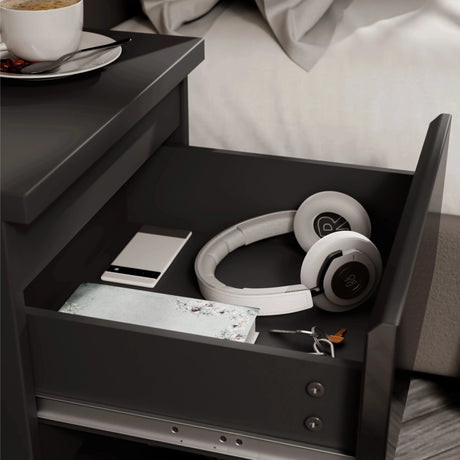[Black]  close-up of open drawer in black bedside table showing phone headphones notebook and keys