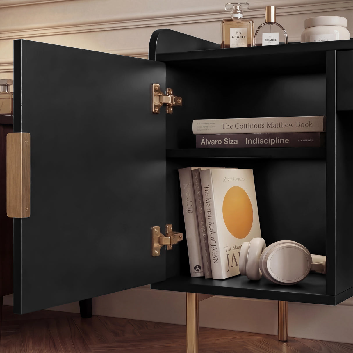 View of open shelves inside a black makeup table, showing books and accessories on display with gold legs