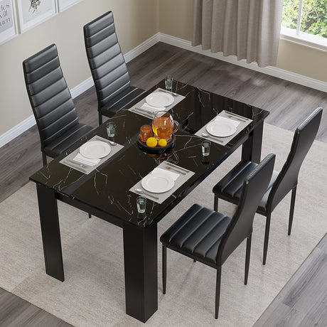 top-down view of black dining table and black chairs set, arranged with plates on high gloss black marble tabletop