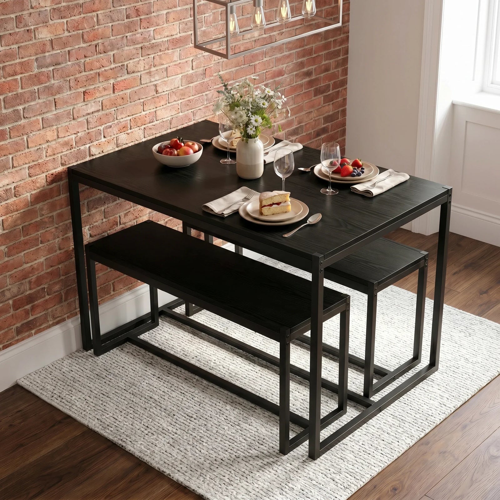 [Black] Orvak dining table with two benches tucked underneath in an industrial brick-wall dining room, styled with fruit bowl and flower vase
