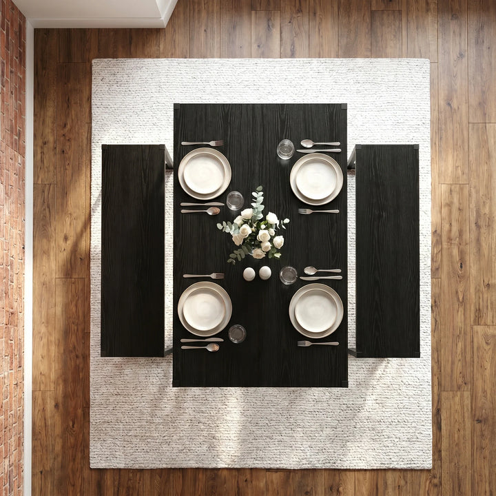 [Black] Orvak dining table seen from directly above with two benches, four place settings, cutlery, glassware, and a white rose centrepiece