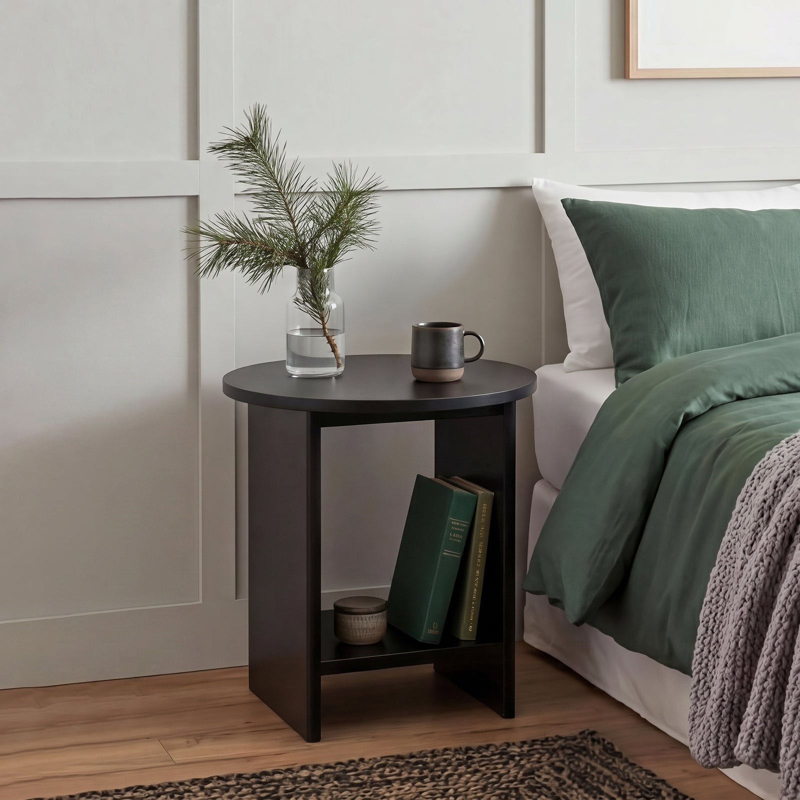 [Black] Small Round Side Table with Shelf Living Room used as bedside table beside green-dressed bed with glass vase and mug on top and books on lower shelf