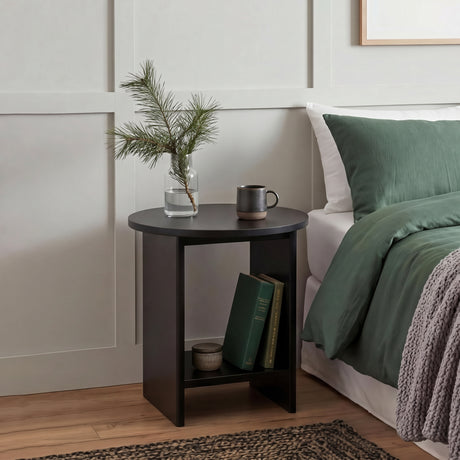 [Black] Small Round Side Table with Shelf Living Room used as bedside table beside green-dressed bed with glass vase and mug on top and books on lower shelf