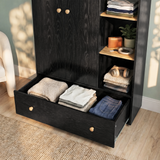 [Black] Selby wardrobe bottom drawer pulled open showing folded clothing inside alongside open shelves with accessories and plant