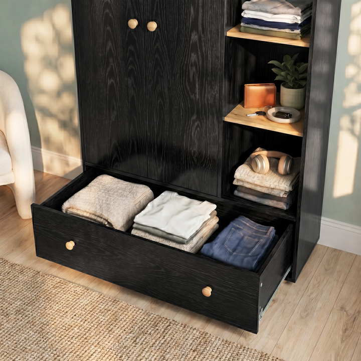 [Black] Selby wardrobe bottom drawer pulled open showing folded clothing inside alongside open shelves with accessories and plant