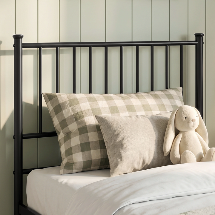 [Black | Single] Headboard close-up showing vertical bars, capped posts, checked pillow, textured cushion, and a toy bunny.