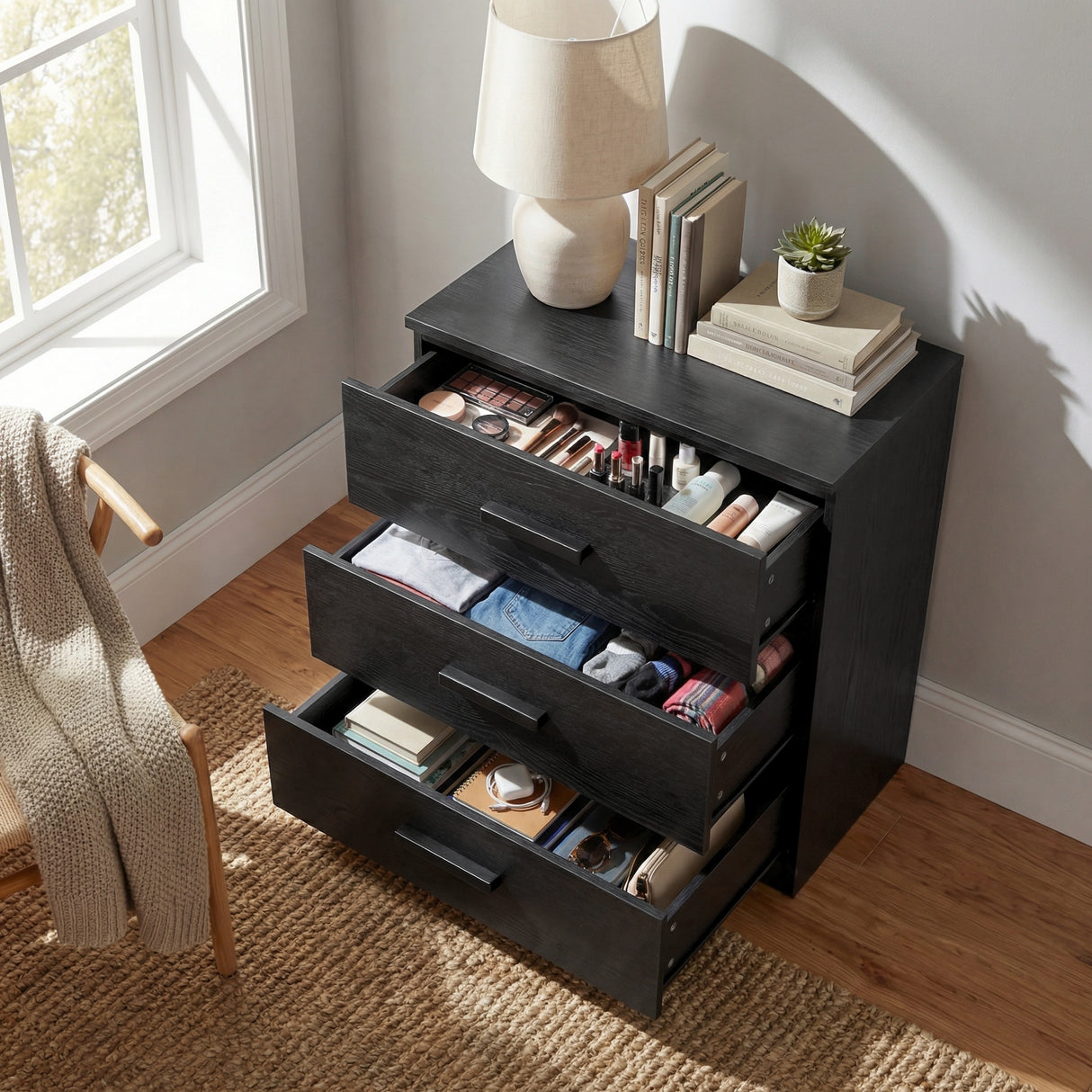 [Black] 3 drawer chest shown at angle with drawers open, displaying depth and internal storage space
