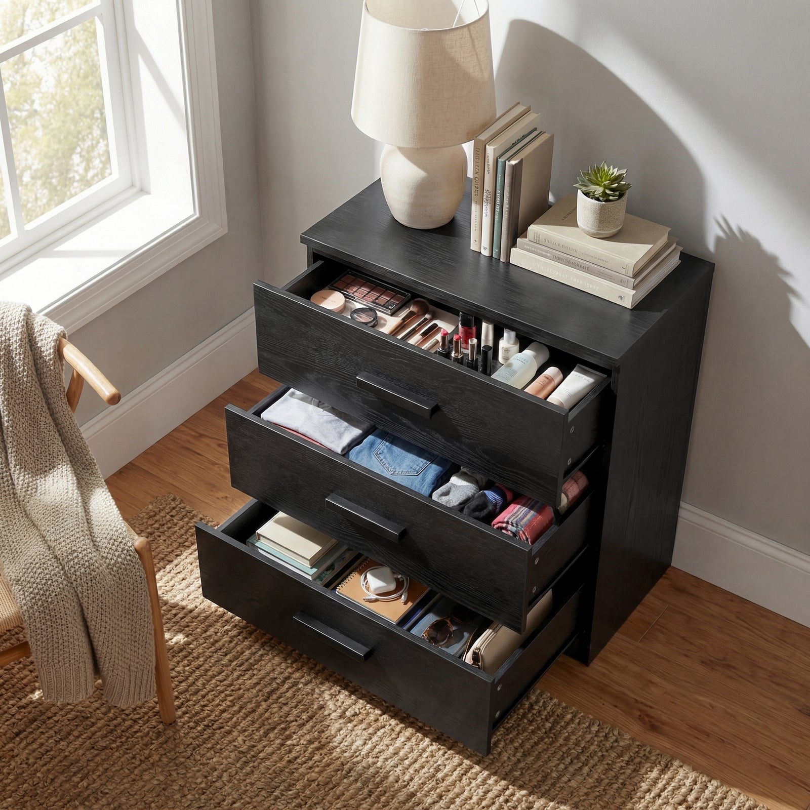 [Black] 3 drawer chest shown at angle with drawers open, displaying depth and internal storage space