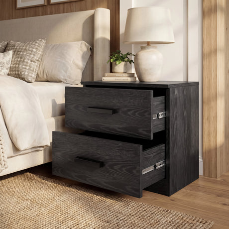 Black two drawer bedside table positioned in a bedroom setting against a wall and soft furnishings