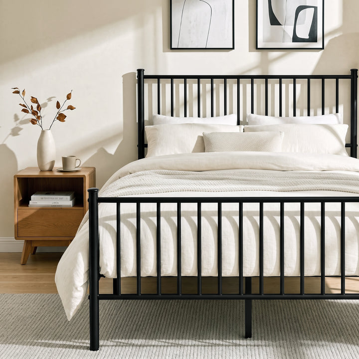 [Black | Double] Metal bed front close-up view of vertical bar footboard, tall headboard, cream bedding & centre support leg.