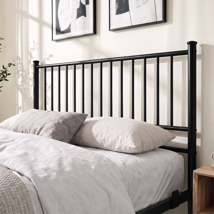 [Black | Double] Black double bed close-up view of tall vertical-bar metal headboard behind layered cream pillows and bedding