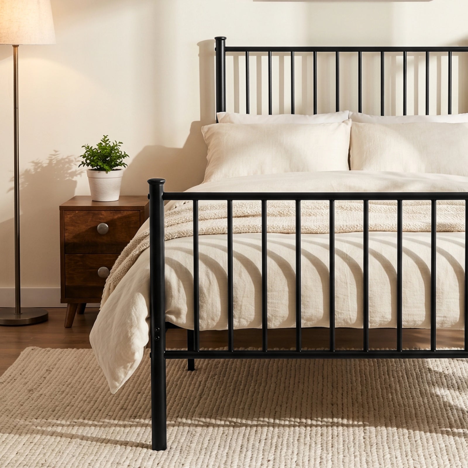 [Black | Single] Metal bed foot-end view with bar headboard and footboard, cream-white bedding, centre leg, lamp and plant.