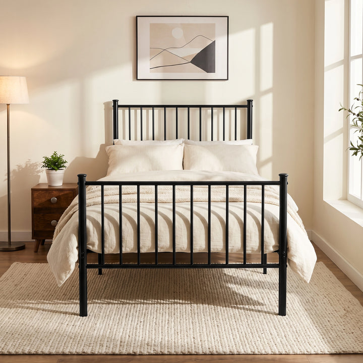 [Black | Single] Front view of metal bed with cream-white bedding, bar ends, centre leg, bedside plant, lamp & bright window.