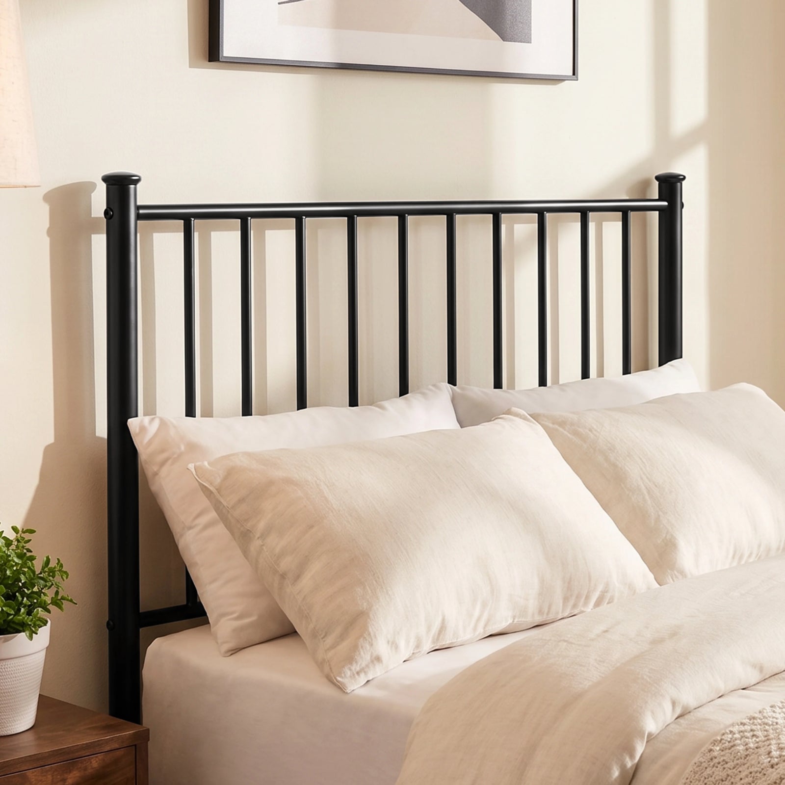 [Black | Single] Metal bed close-up of tall bar headboard with cream-white pillows, wooden bedside table, plant and wall art.