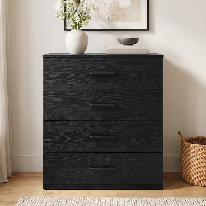 [Black] Front view of a black wood grain 4-drawer chest with sleek black handles, styled with vase decor on a wooden floor