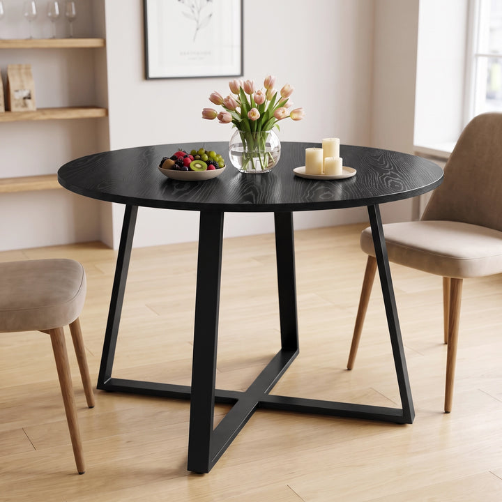 [Black Wood] Round dining table in a bright room with fruit, flowers and candles on top, with two chairs beside it.