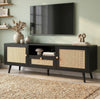[Black] Wovena Black Rattan TV Unit with 2 Door Storage three-quarter view in sage green room with rattan door panels, central drawer and tapered black legs