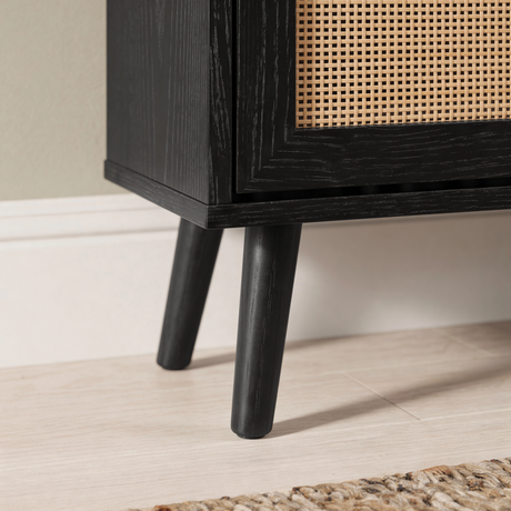 [Black] Wovena shoe cabinet close-up of solid black tapered mid-century leg detail and lower rattan panel corner showing wood grain texture finish