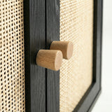 [Black] Wovena close-up of two solid cylindrical oak knob handles on the ebonised centre door divider, with open-weave rattan panels filling the frame on both sides