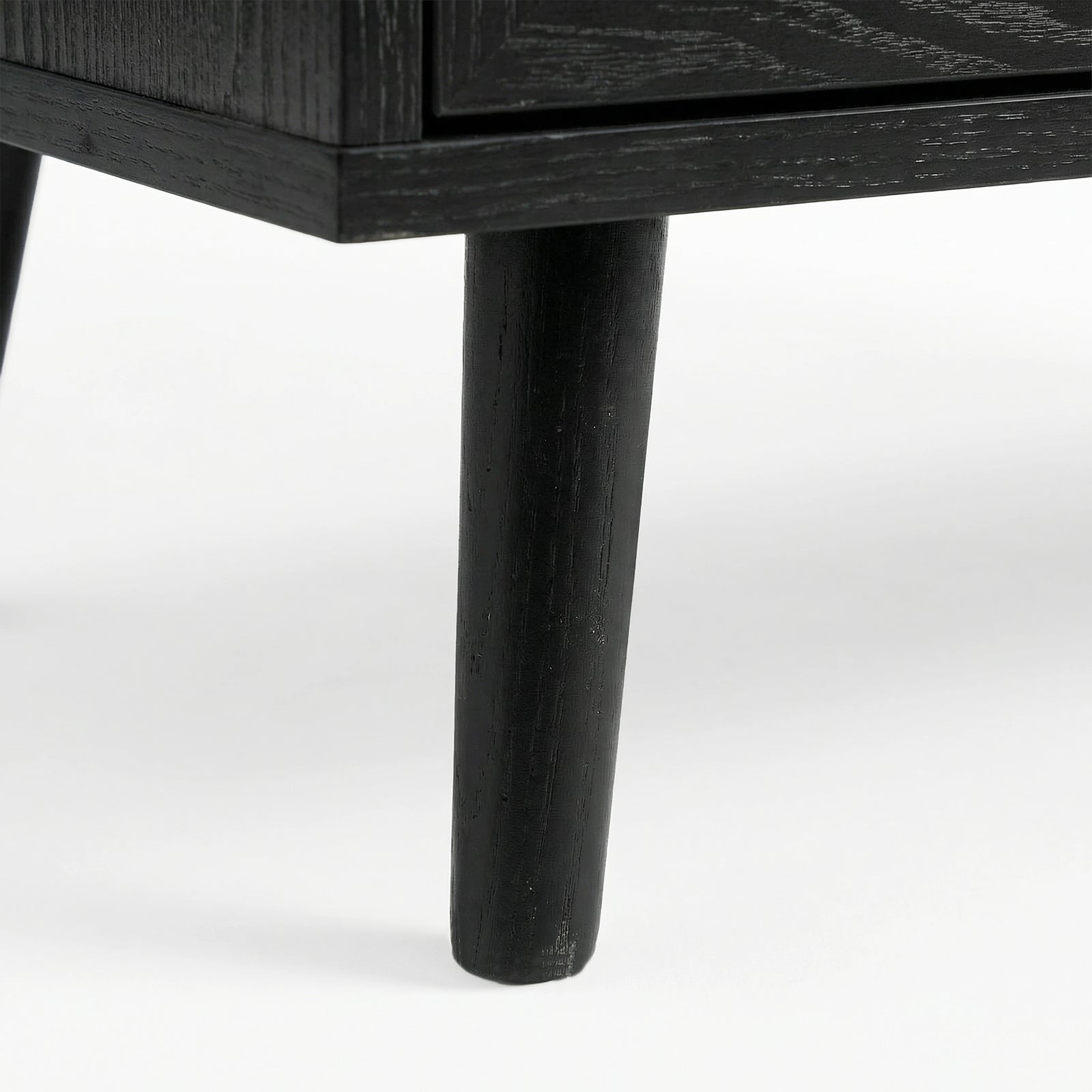 [Black] close-up of a tapered black leg on the Wovena sideboard with wood grain showing through the dark finish