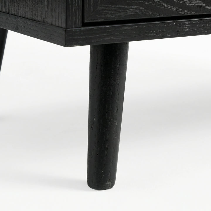 [Black] close-up of a tapered black leg on the Wovena sideboard with wood grain showing through the dark finish