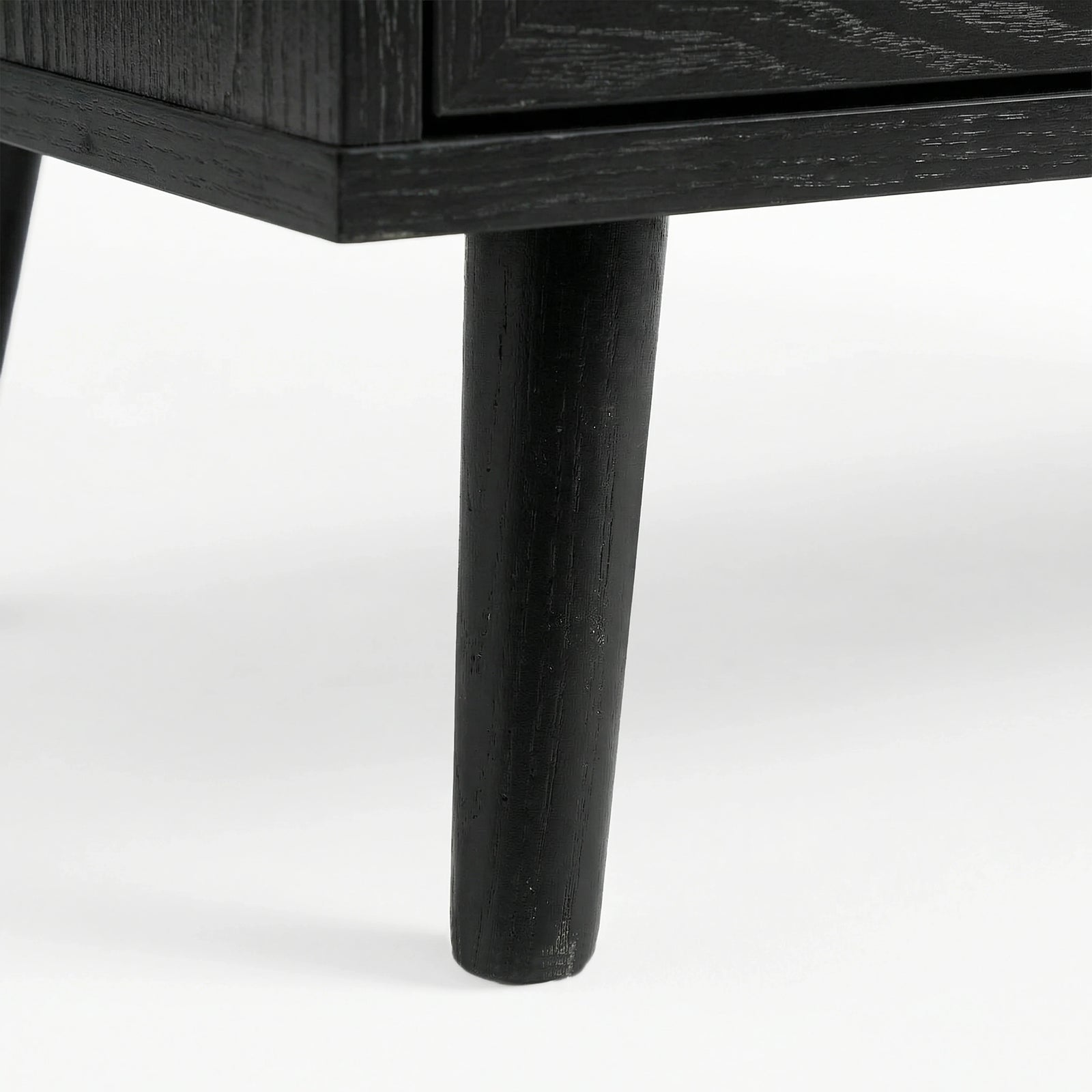 [Black] close-up of a tapered black leg on the Wovena sideboard with wood grain showing through the dark finish