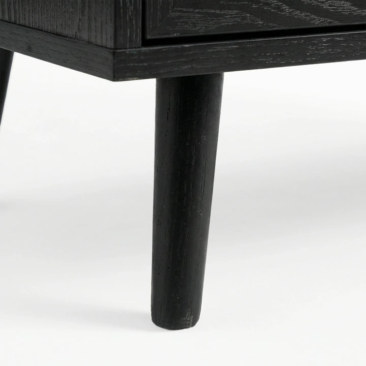 [Black] close-up of a tapered black leg on the Wovena sideboard with wood grain showing through the dark finish